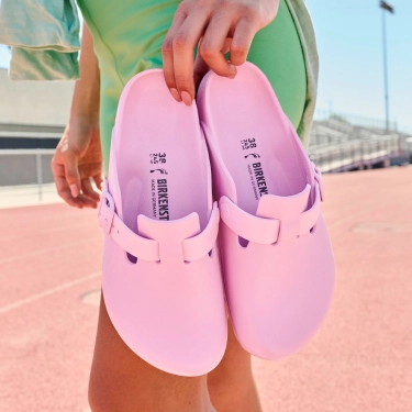 Two pink loafers being held up.