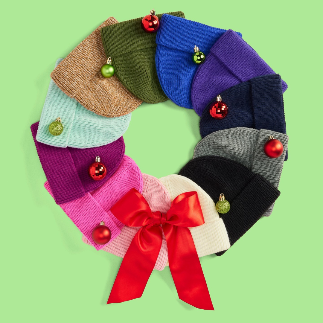 A knit wreath made of different colored beanies with a red ribbon